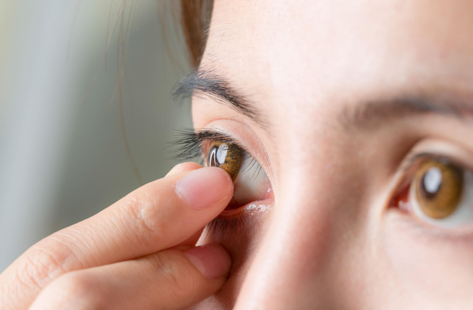 A close-up shot of a young woman removing her contact lenses before sleeping.