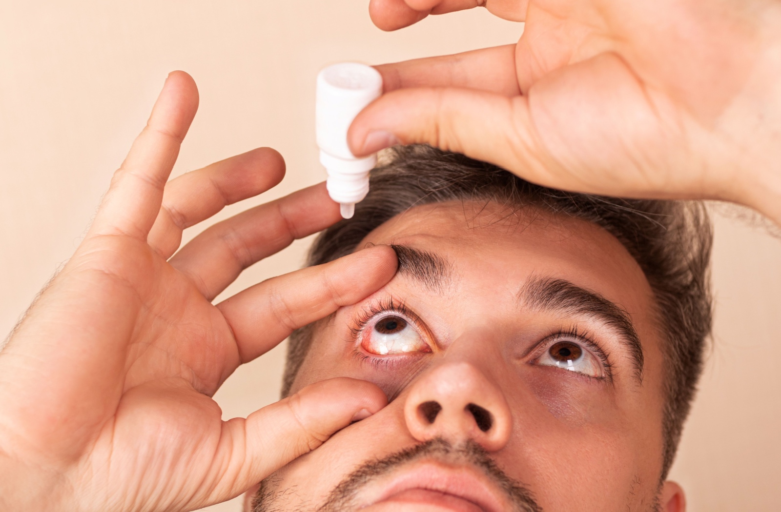 Close up of man applying eye drops.
