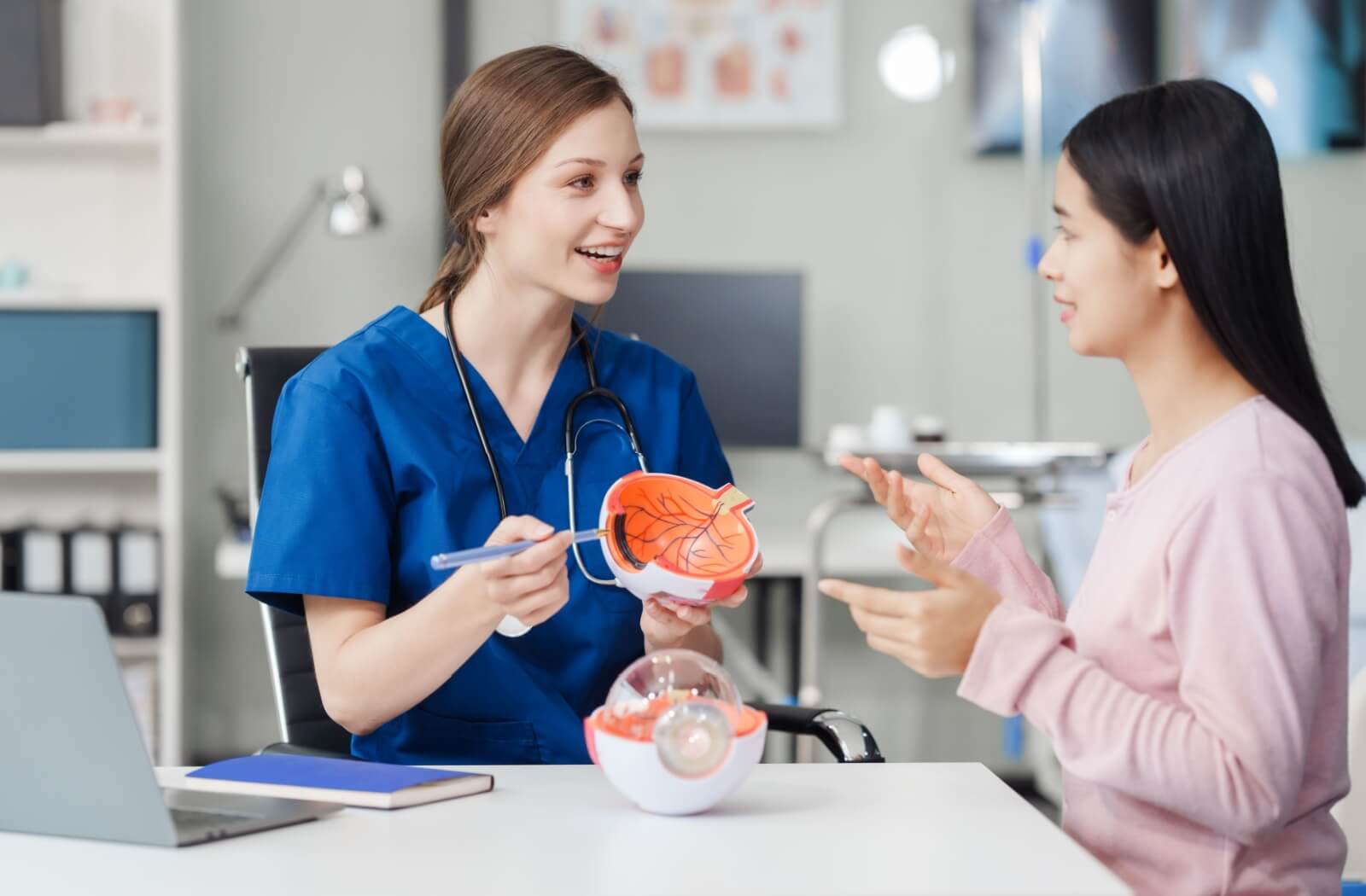 An optometrist uses a model to explain how glaucoma develops to their patient.