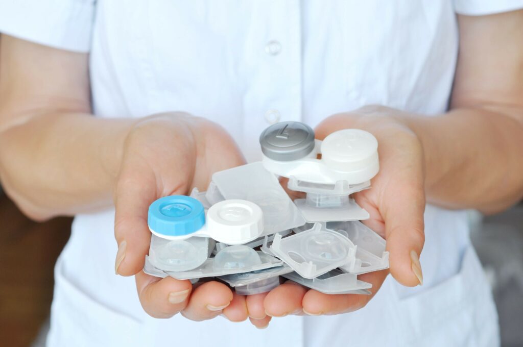 A close-up of an optometrist holding a variety of different contact lens packages.