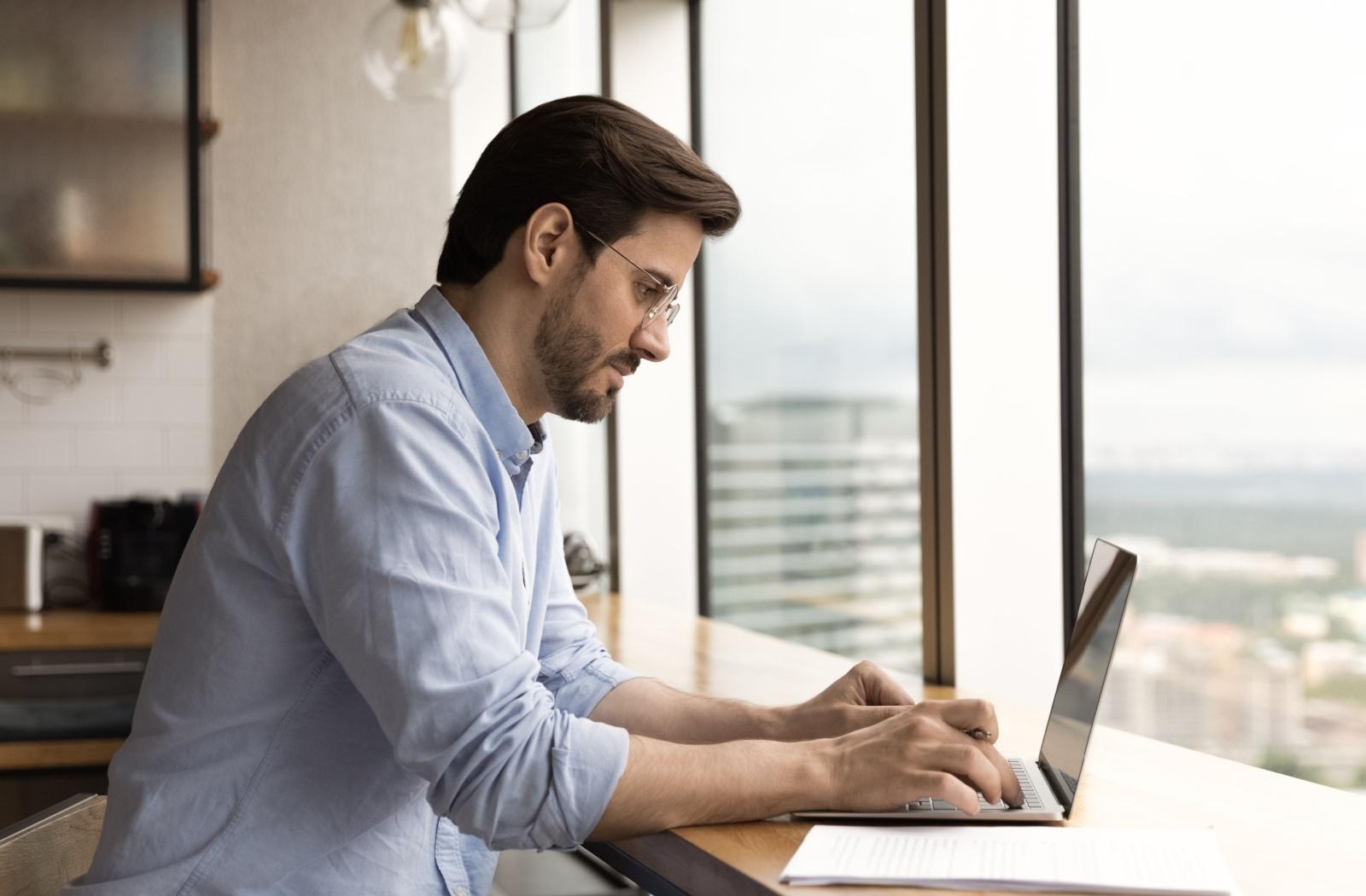 a person sitting a computer and staring at the screen while wearing a pair of glasses.